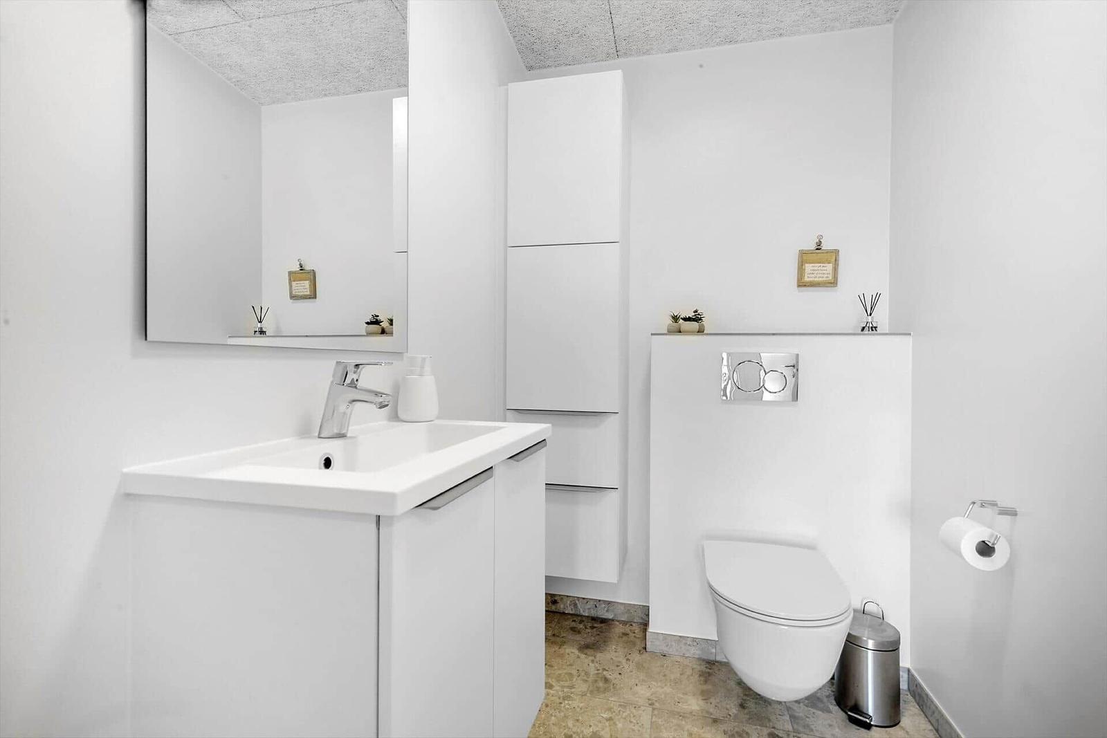 Badezimmer mit Waschbecken, Spiegel, Toilette und Schränken.