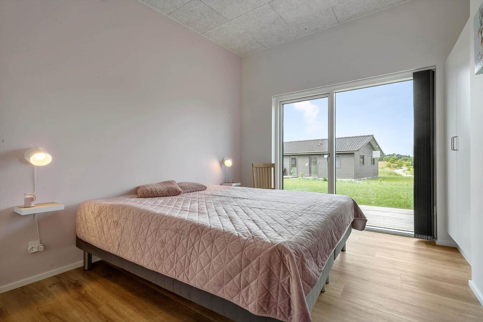 Schlafzimmer mit Bett, Schlafcouch und großem Fenster zur Aussicht.