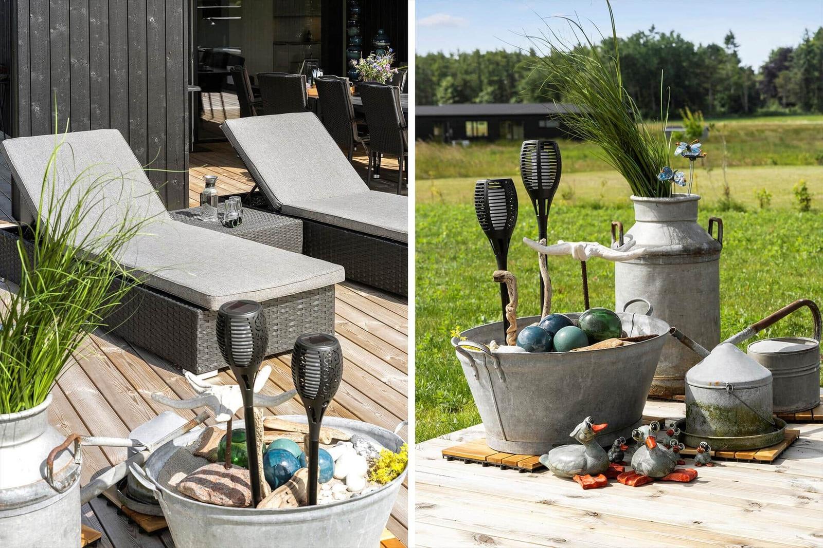 Terrasse mit Liegen und dekorativen Metallgefäßen auf Holzdielen.