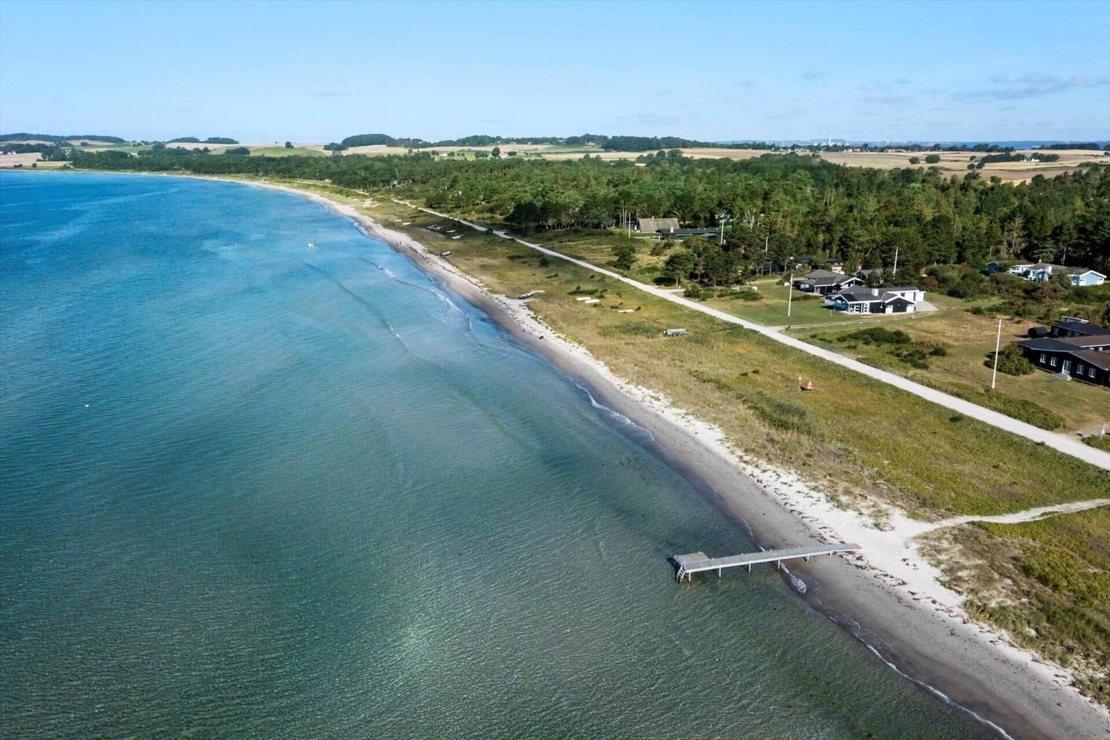 Ausblick auf Strand mit Bootsdock und Ferienhäusern entlang der Küste.