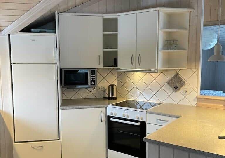 Küche mit Kühlschrank, Mikrowelle und Herd unter Dachschrägen