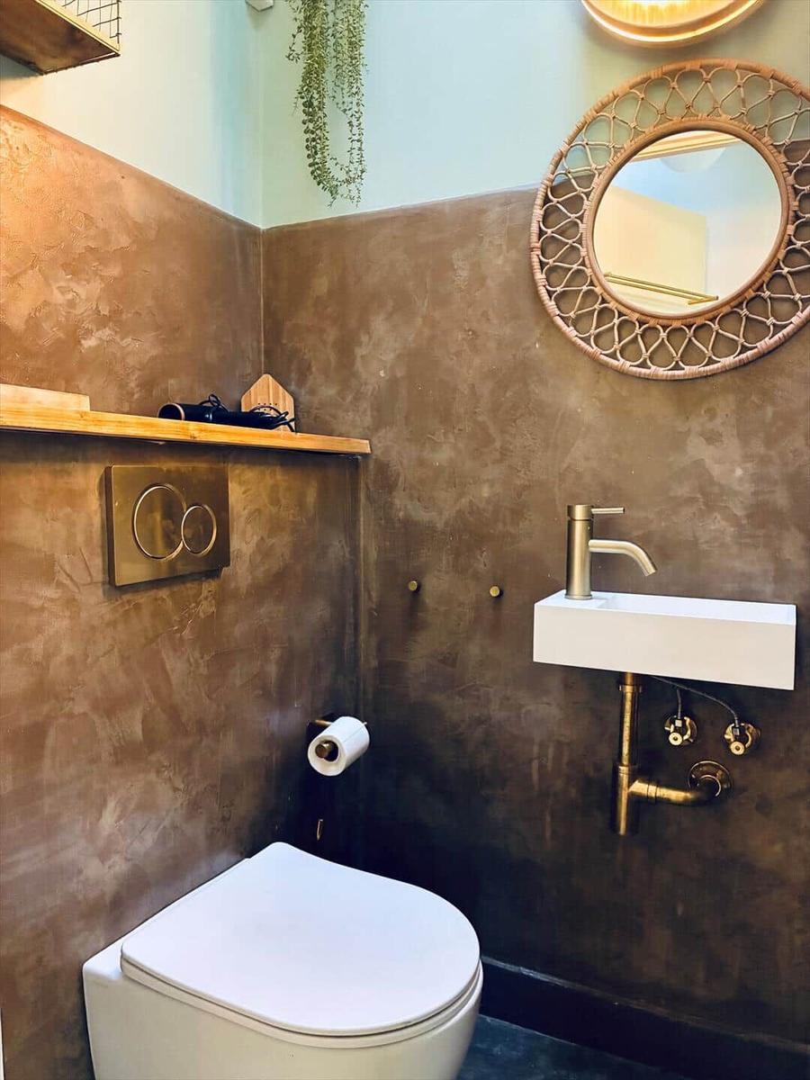 Bathroom with toilet, sink, and round mirror on the wall.