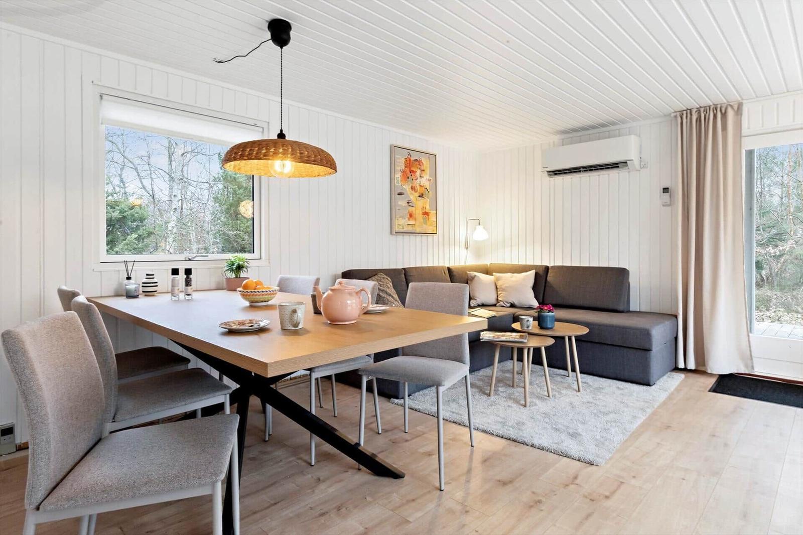 Essbereich mit Tisch, Stühlen und Sofa. Fenster und Tür zu Garten.