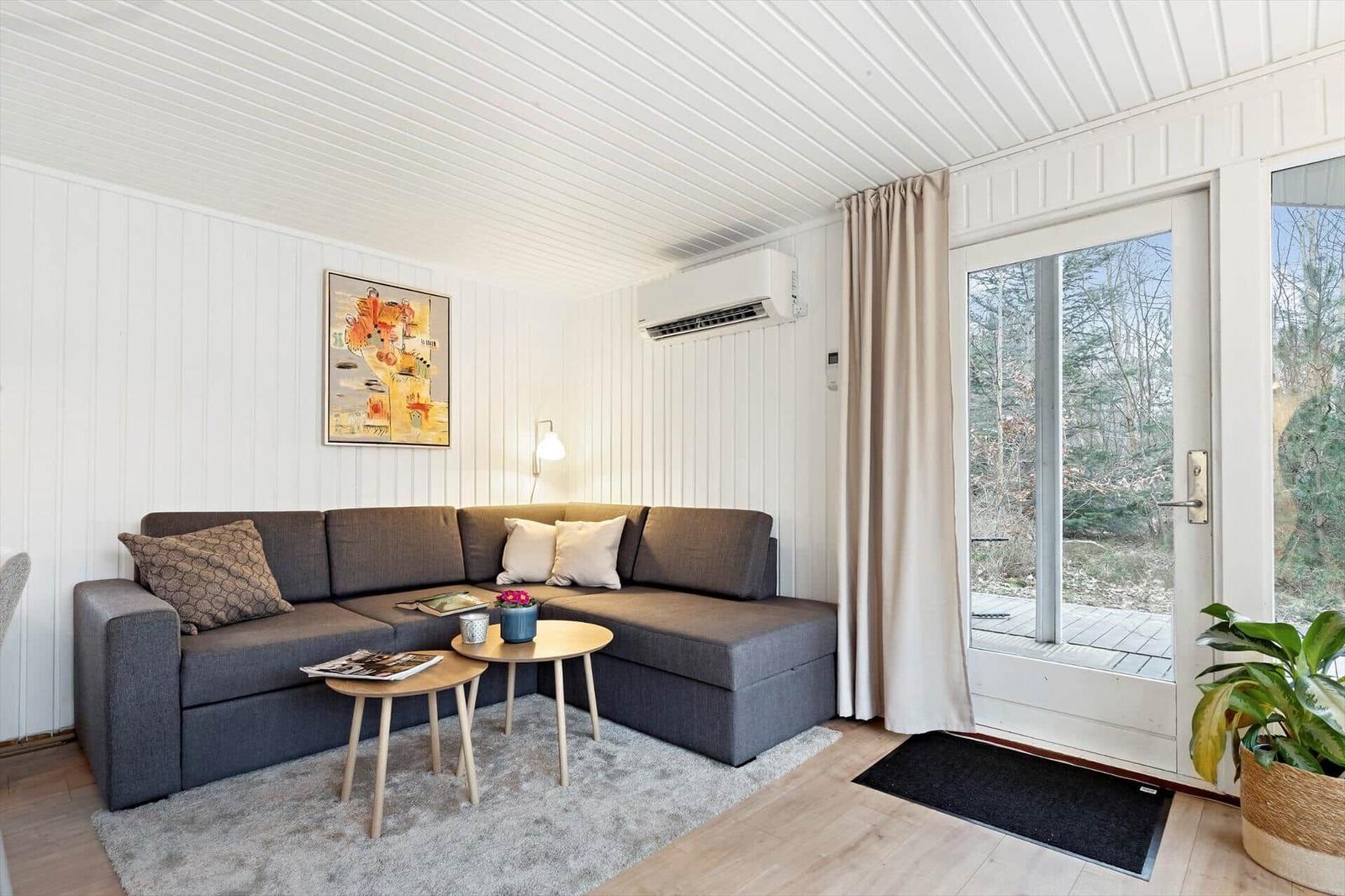 Wohnzimmer mit Ecksofa, Tischen und Blick auf die Terrasse.