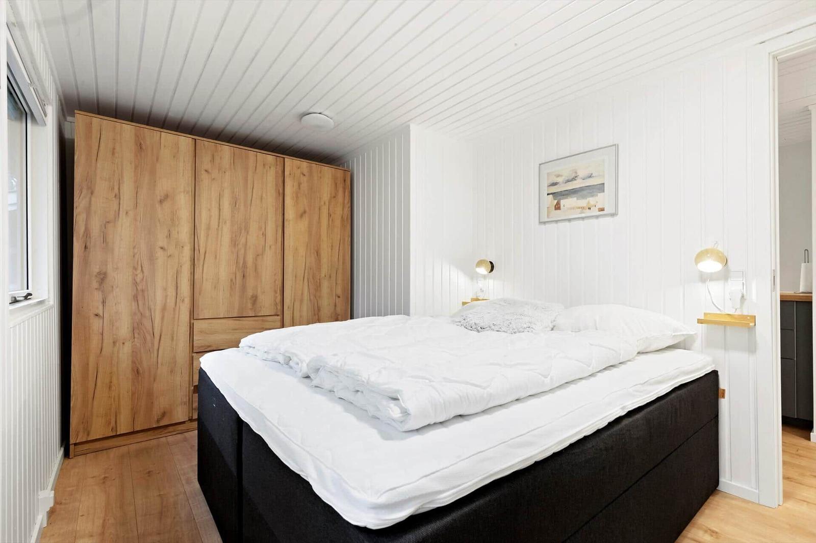 Schlafzimmer mit Bett, Holzschrank und Wandbild.