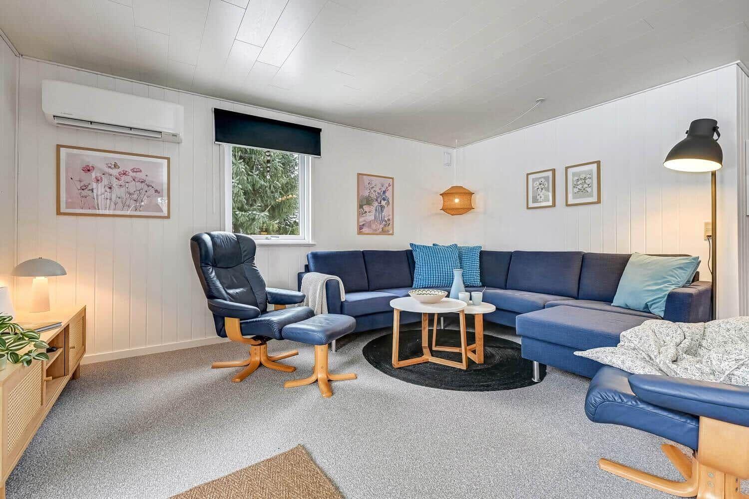Ein Wohnzimmer mit blauem Sofa, zwei blauen Sesseln und einem runden Tisch.