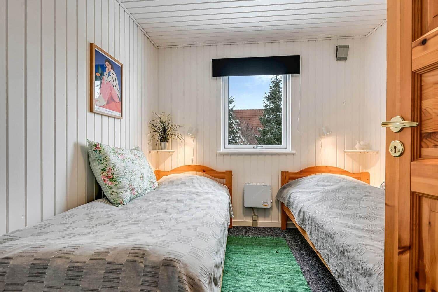 Zwei Betten in einem Raum mit Fenster und grünem Teppich.