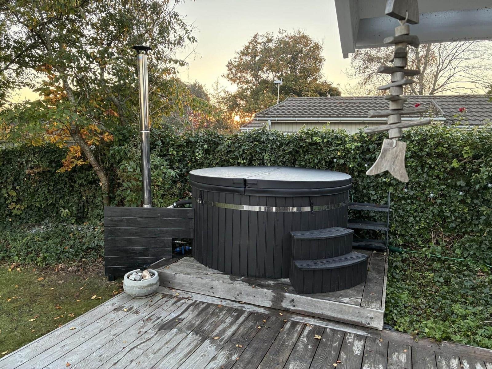Schwarzer Whirlpool auf Holzterrasse mit Pflanzen und Holzdekor