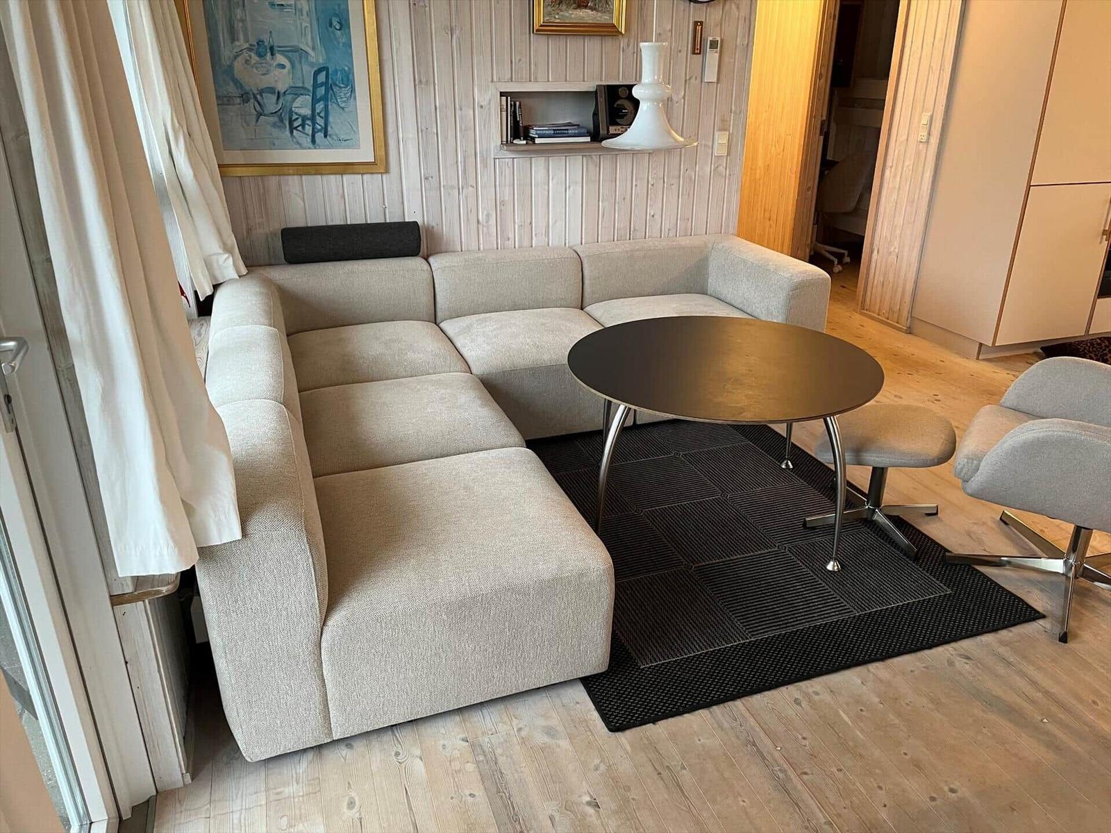 Ein Wohnzimmer mit Ecksofa, runder Tisch und Holzboden.