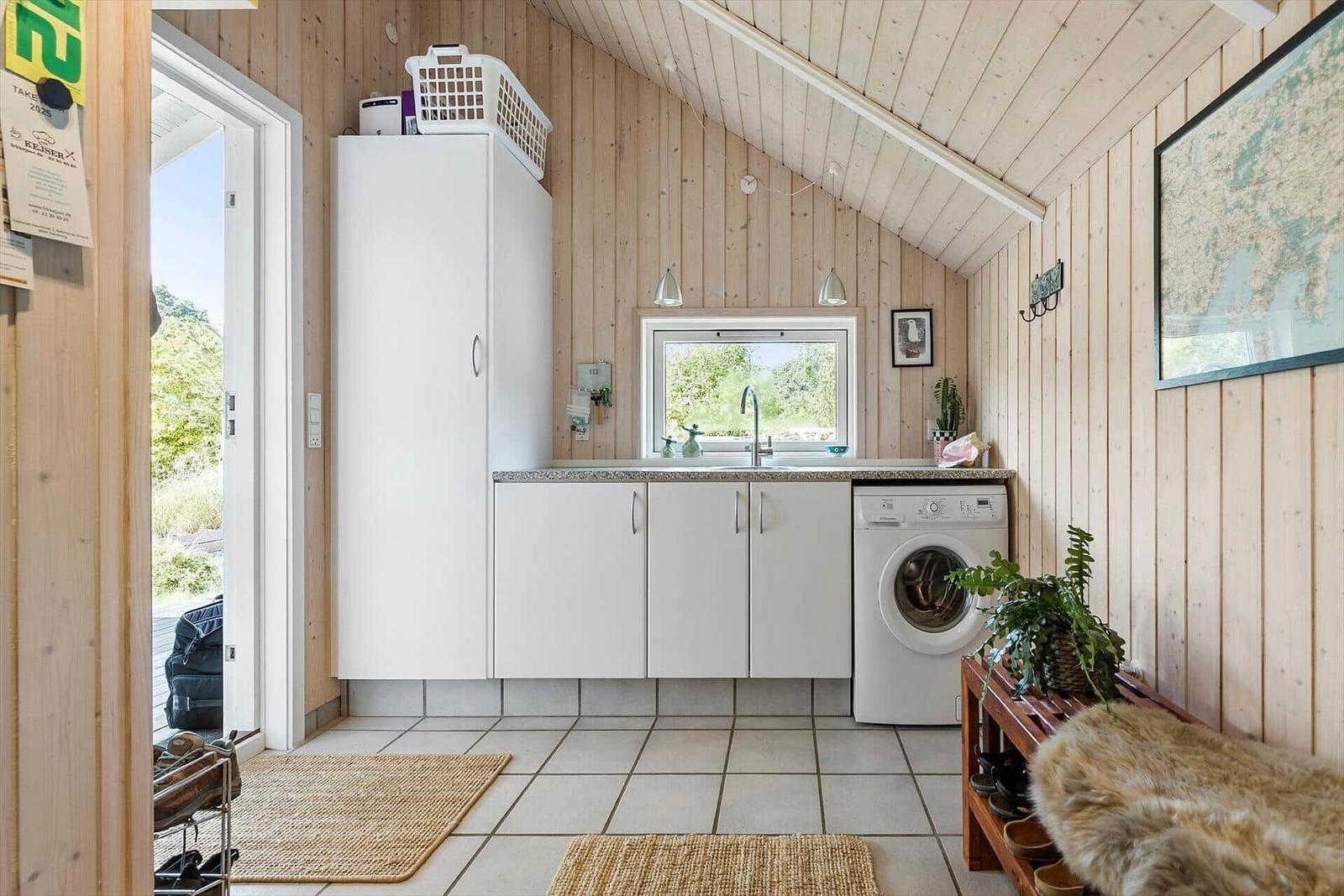 Living area with washing machine, sink, and wood paneling.