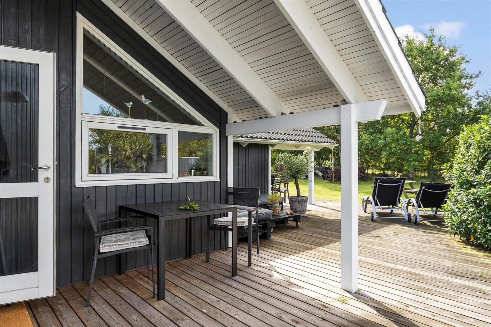 Patio with table, chairs, and lounge chairs under roof