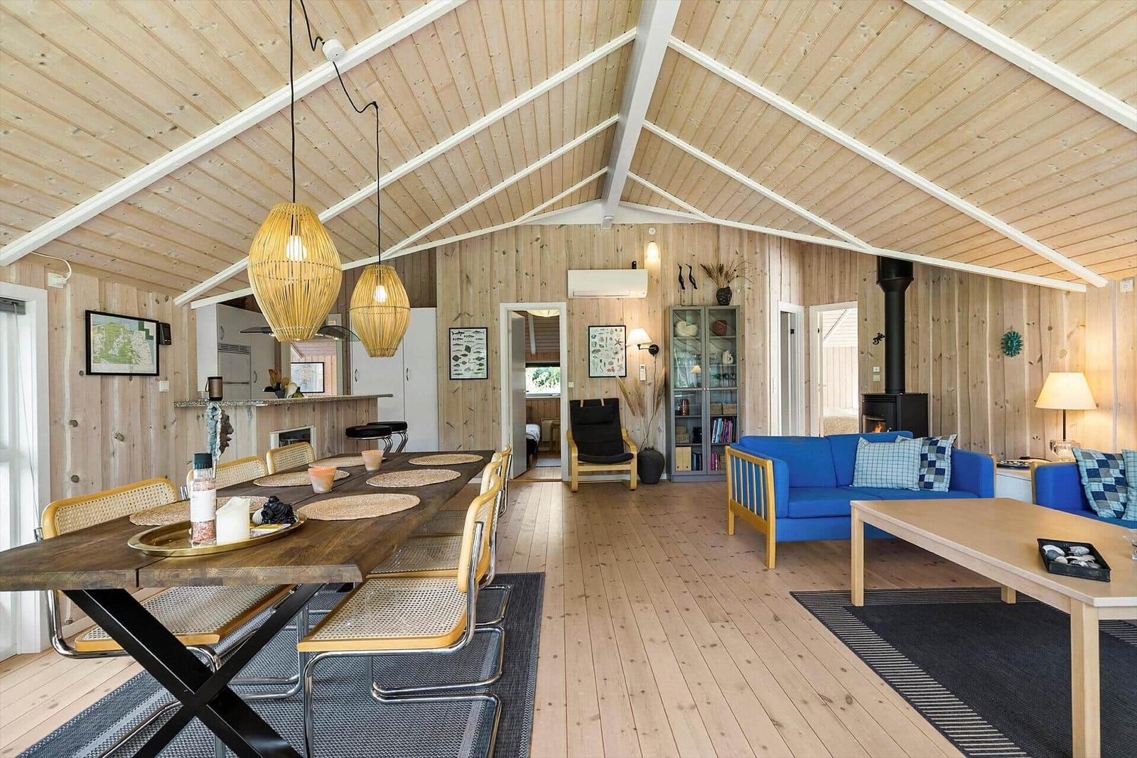 Living and dining area with wooden ceiling, blue sofa, and dining table.