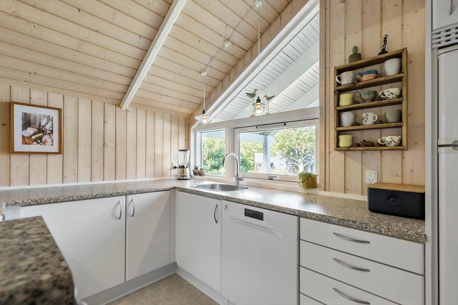 Kitchen with wooden walls, window, sink, and dish rack.