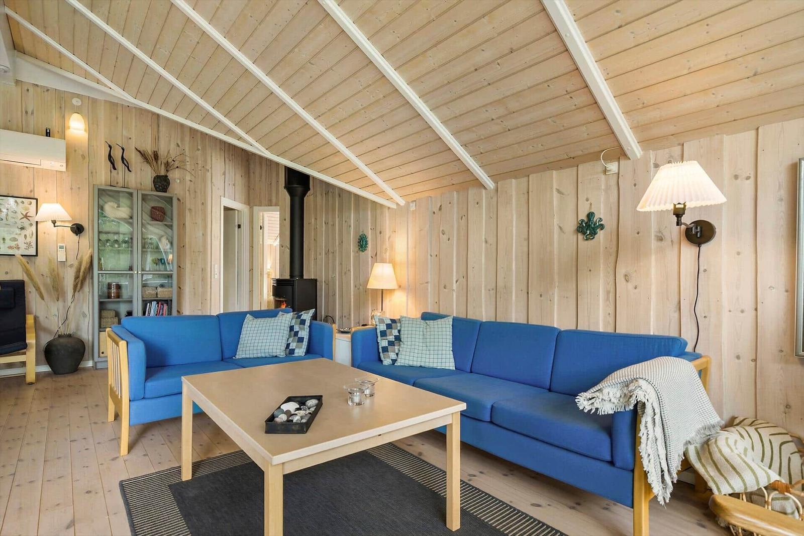 Living room with blue sofas, wooden walls, and fireplace.