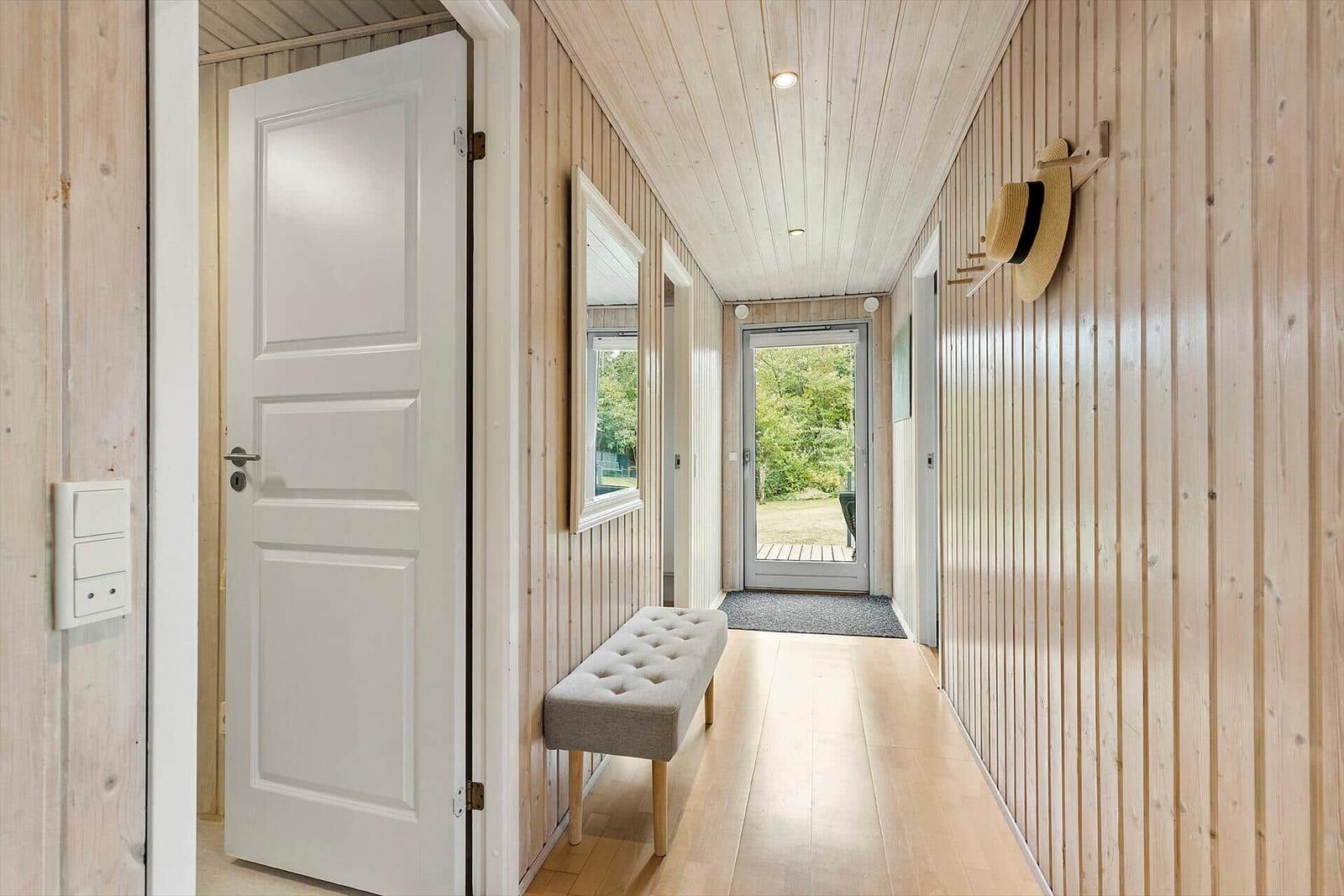 Hallenflur mit Holzwänden, Sitzbank und Tür zum Garten.