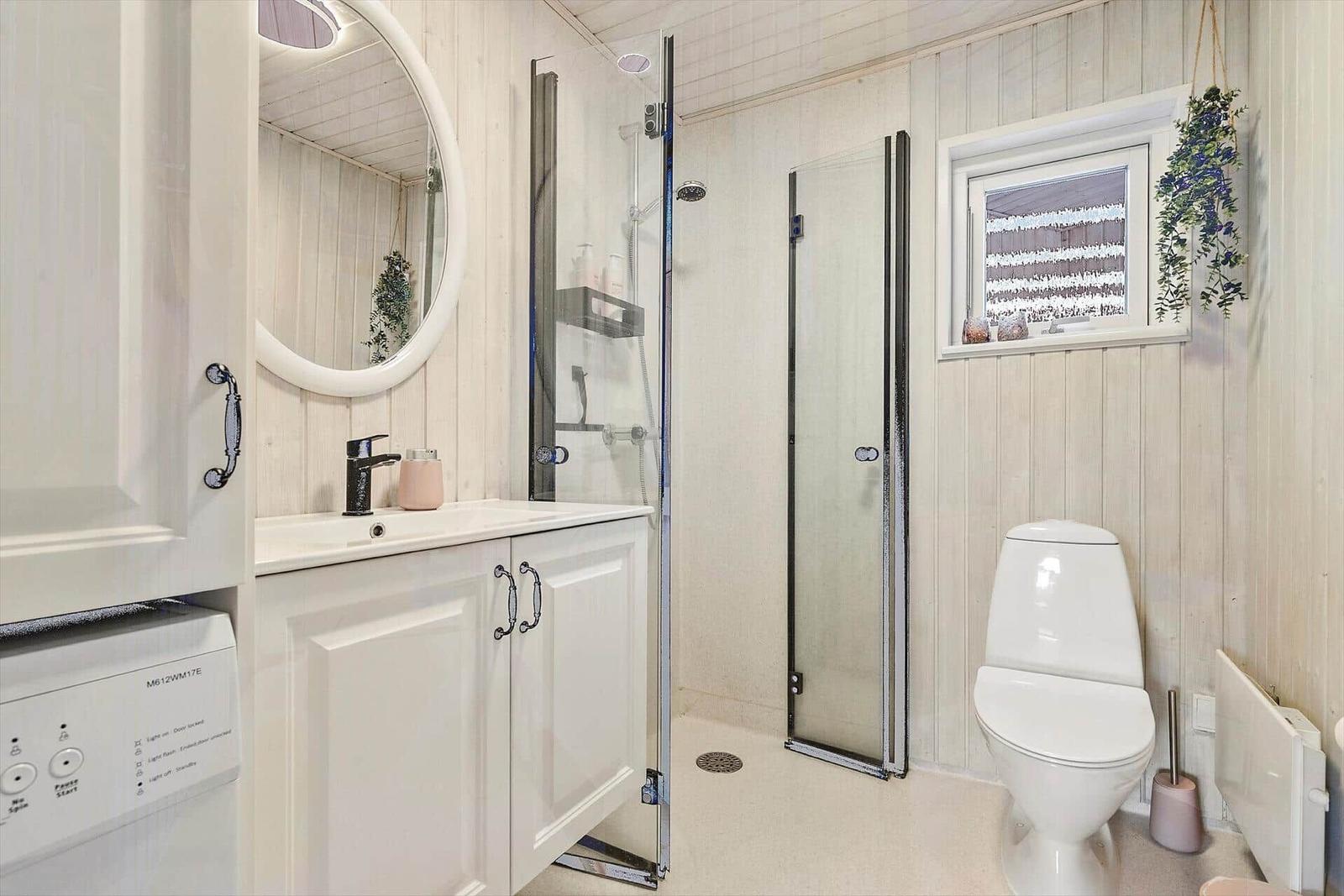 Badezimmer mit Dusche, Toilette und Waschbecken mit Spiegel.