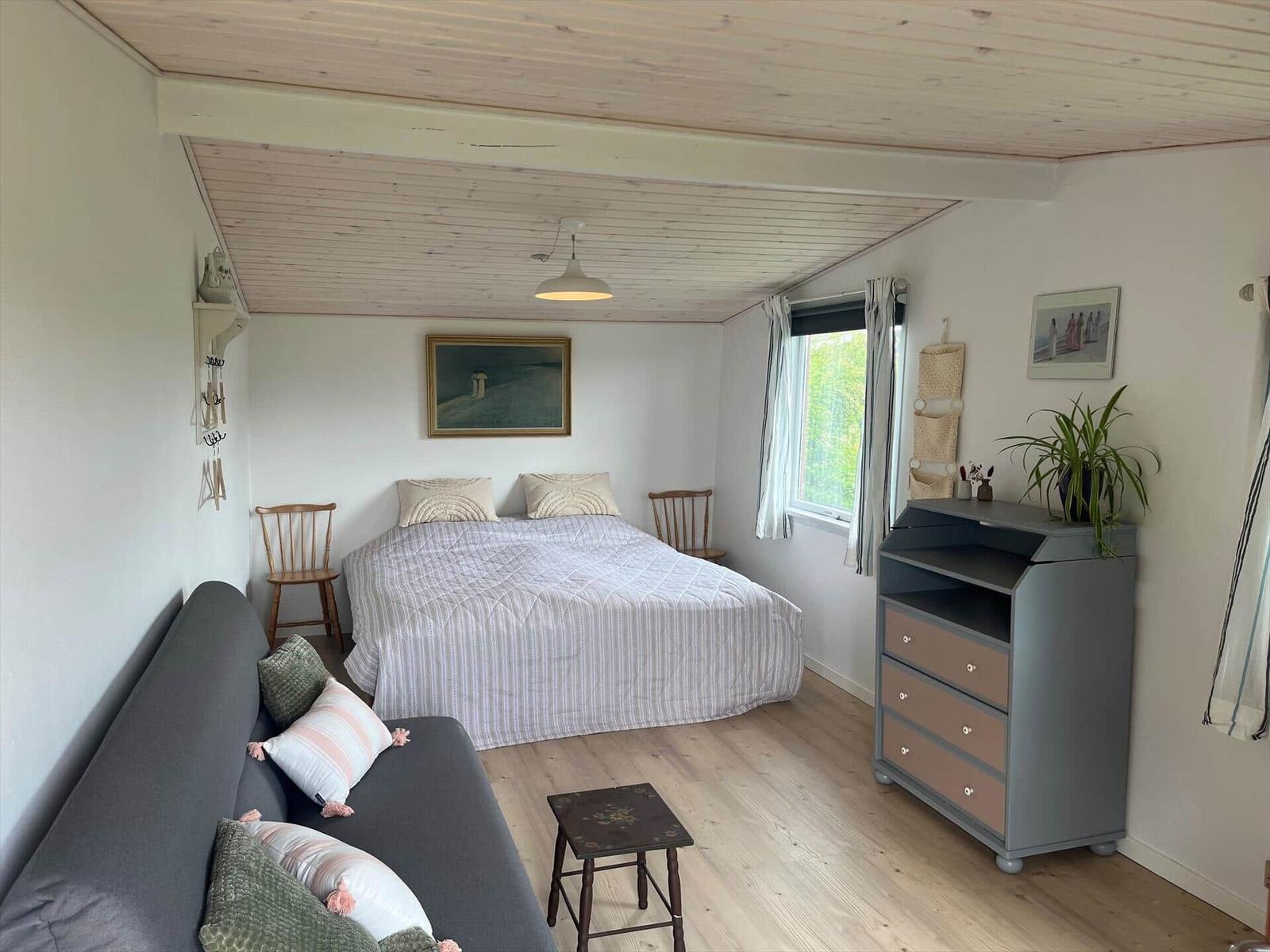 Schlafzimmer mit Bett, Sofa, Schrank und Fenster.