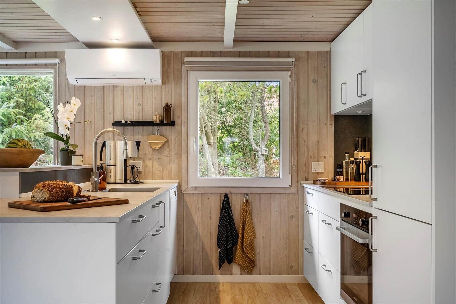 Küche mit Holzwand, Fenster und weißen Schränken
