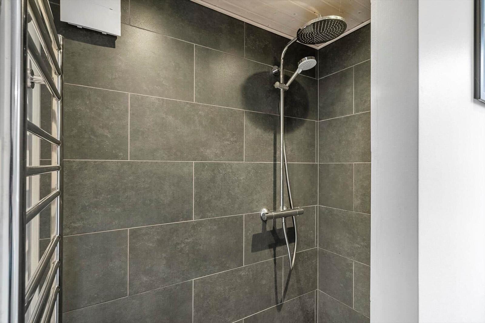 Dusche mit Duschbrause und Handbrause an grauen Fliesen