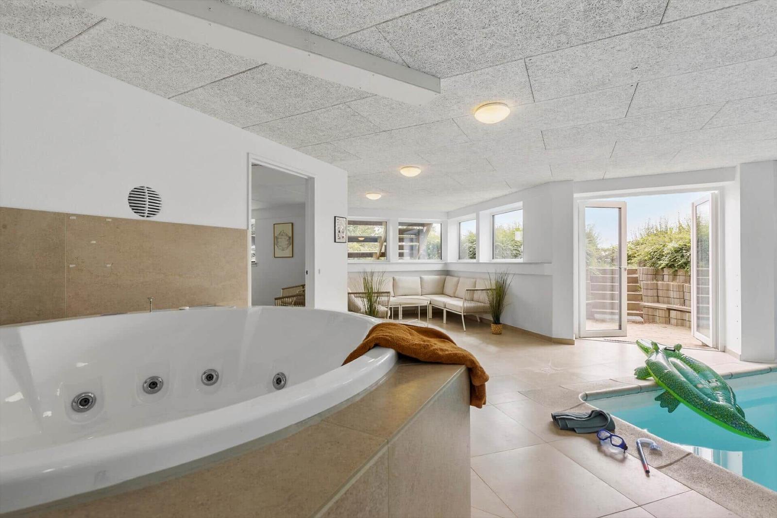 Whirlpool und Pool im Innenbereich mit Sitzgelegenheit und Fenster