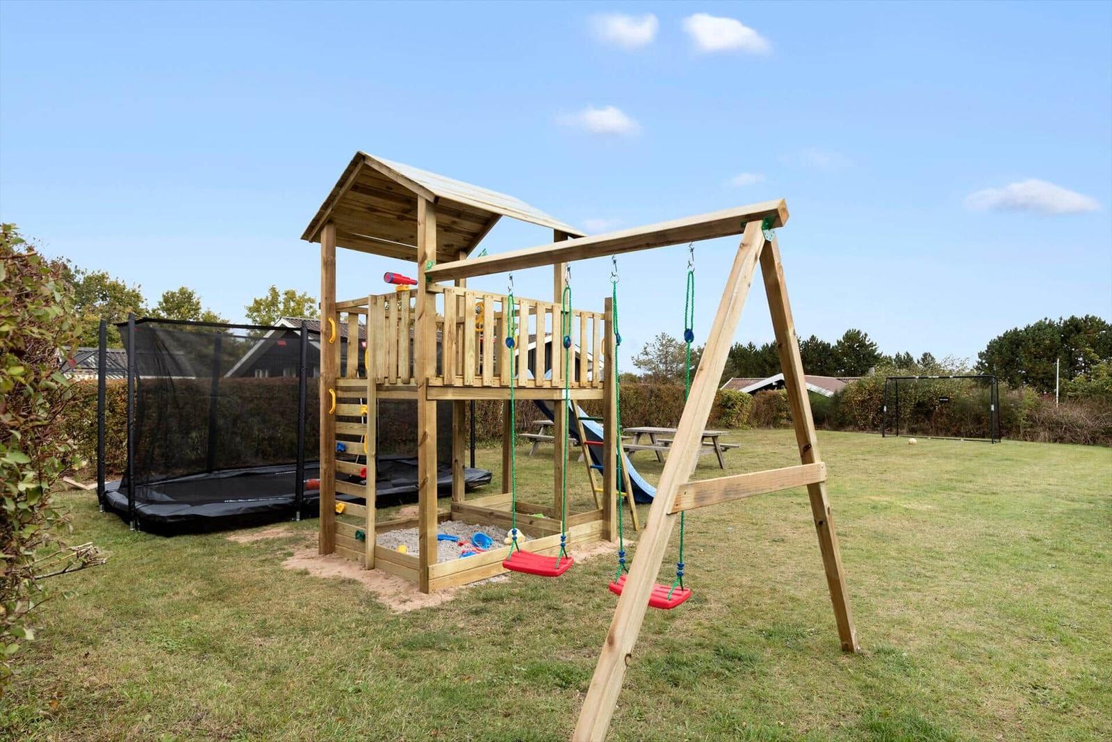 Holzspielplatz mit Schaukel und Sandkasten im Garten