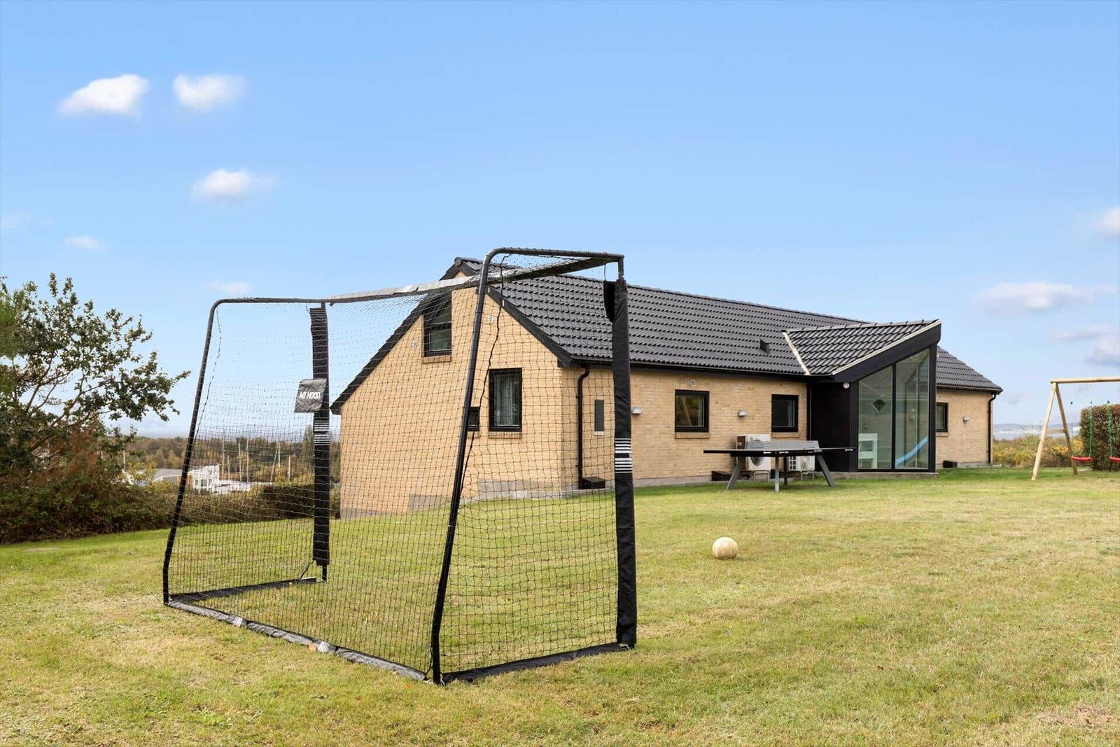 Modernes Haus mit großem Garten, Fußballtor und Spielplatz.
