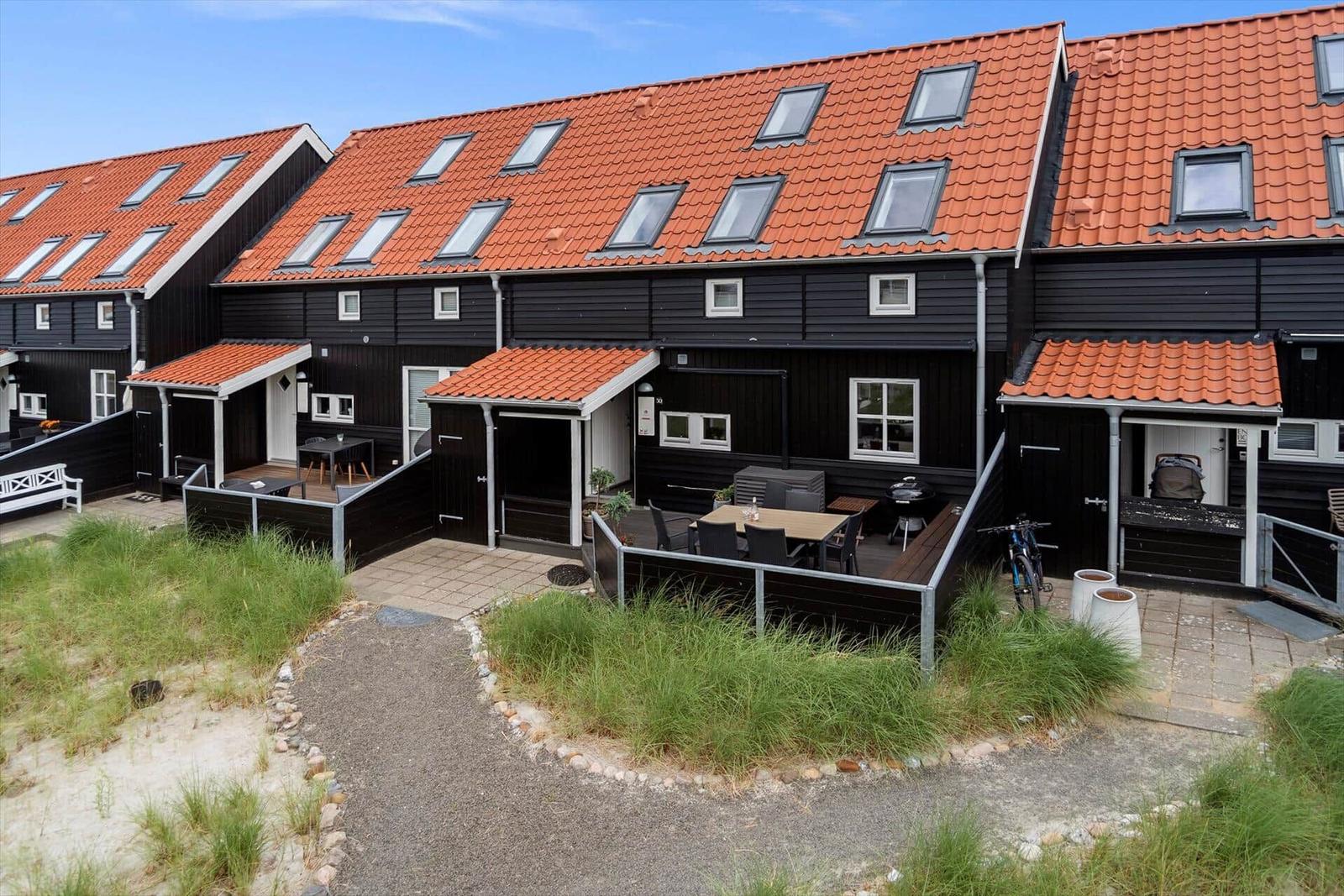 Schwarze Häuser mit roten Dächern und Terrassen im Freien.