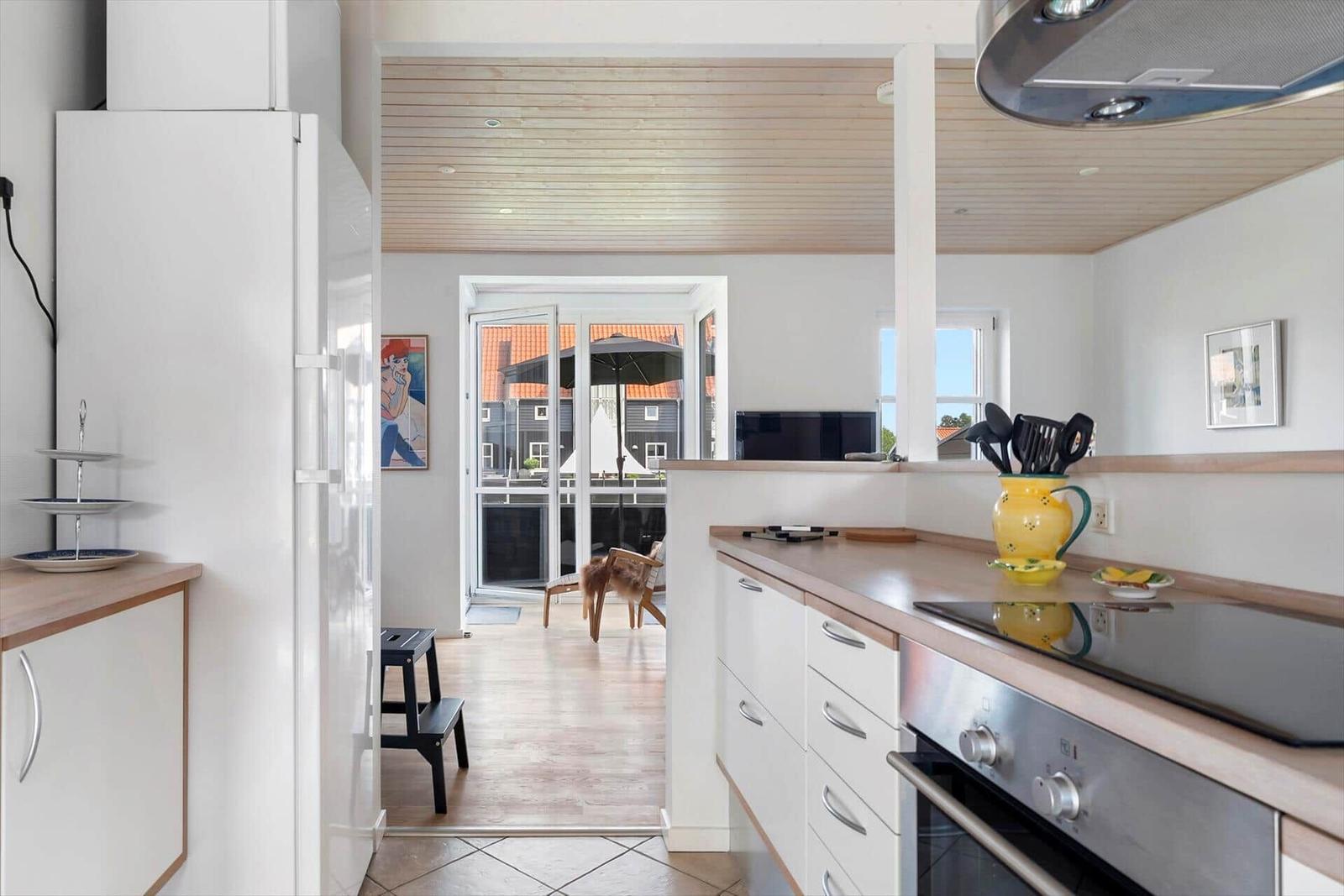 Küche mit Holzboden und Blick auf Terrasse mit Sonnenschirm.