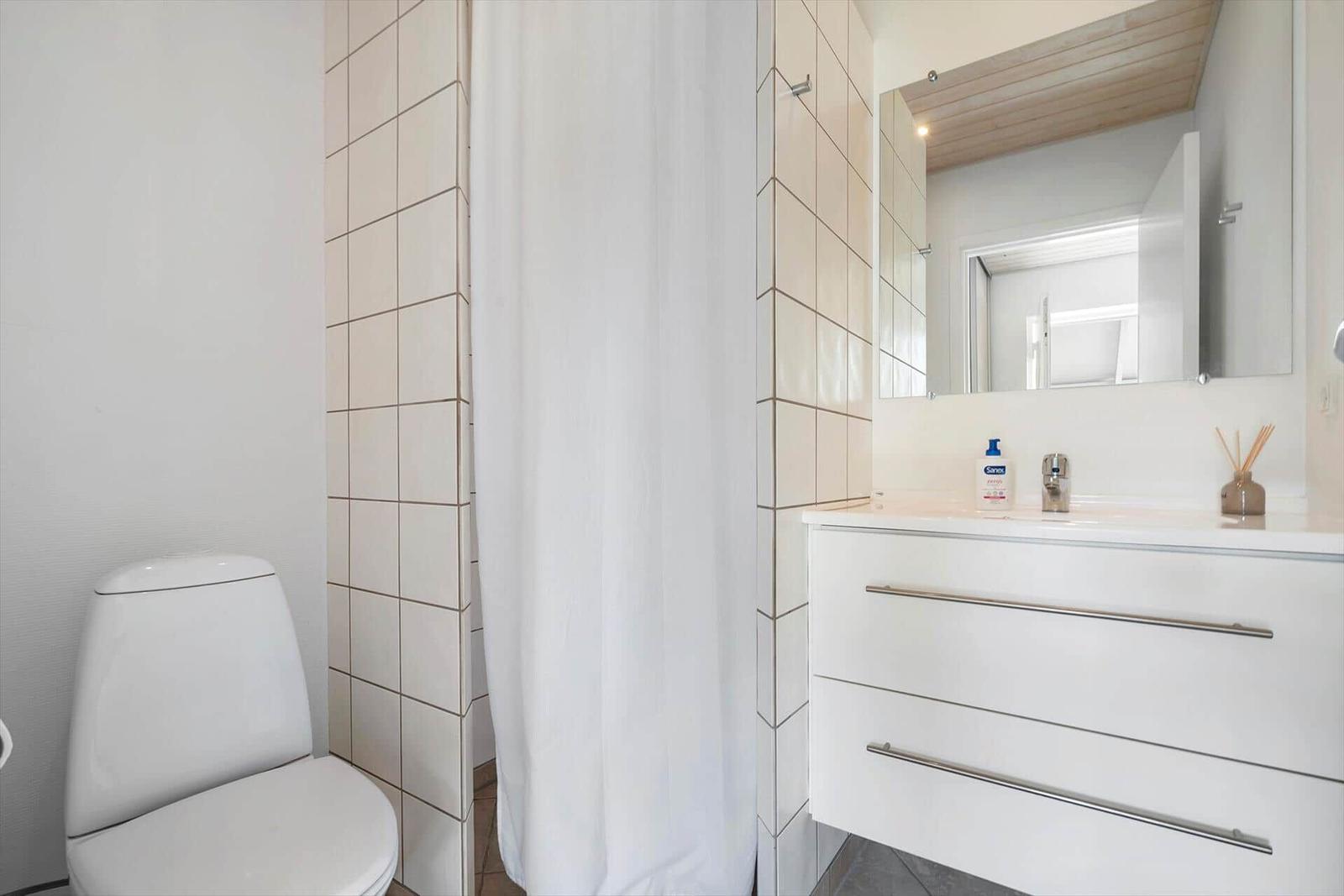 Badezimmer mit Toilette, Dusche und Waschbecken mit Spiegel.