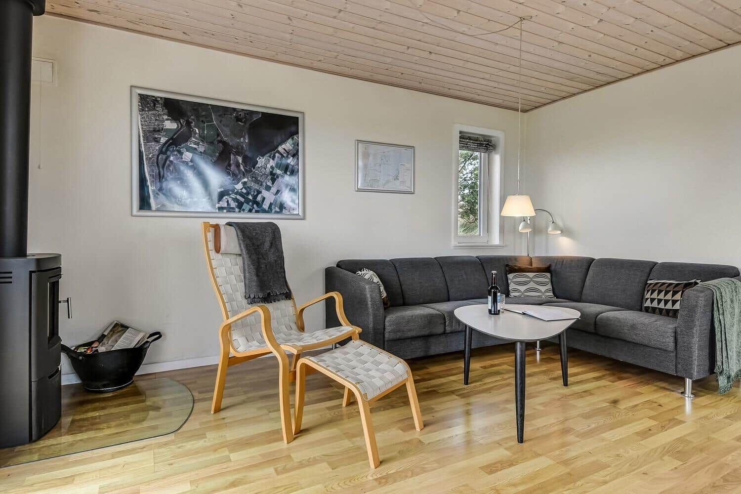 Wohnzimmer mit Sofa, Stuhl und Holzboden. An der Wand hängt ein Bild.
