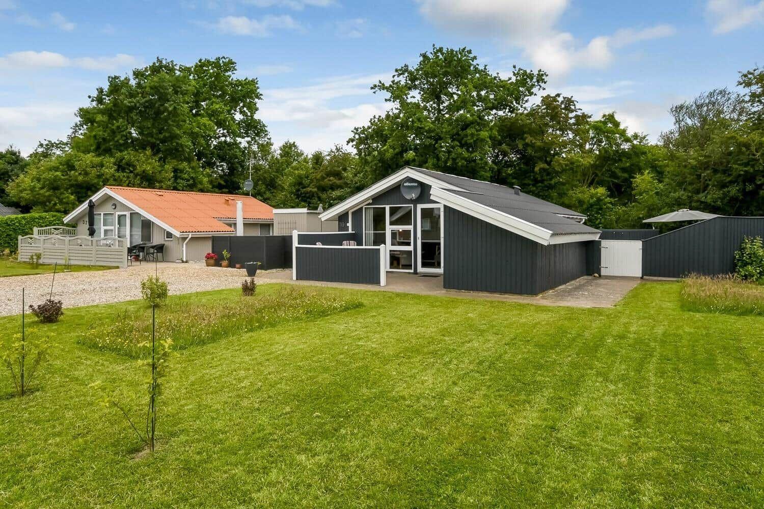 Modernes Ferienhaus mit Garten und Terrasse. Hintergrund: Bäume und klarer Himmel.
