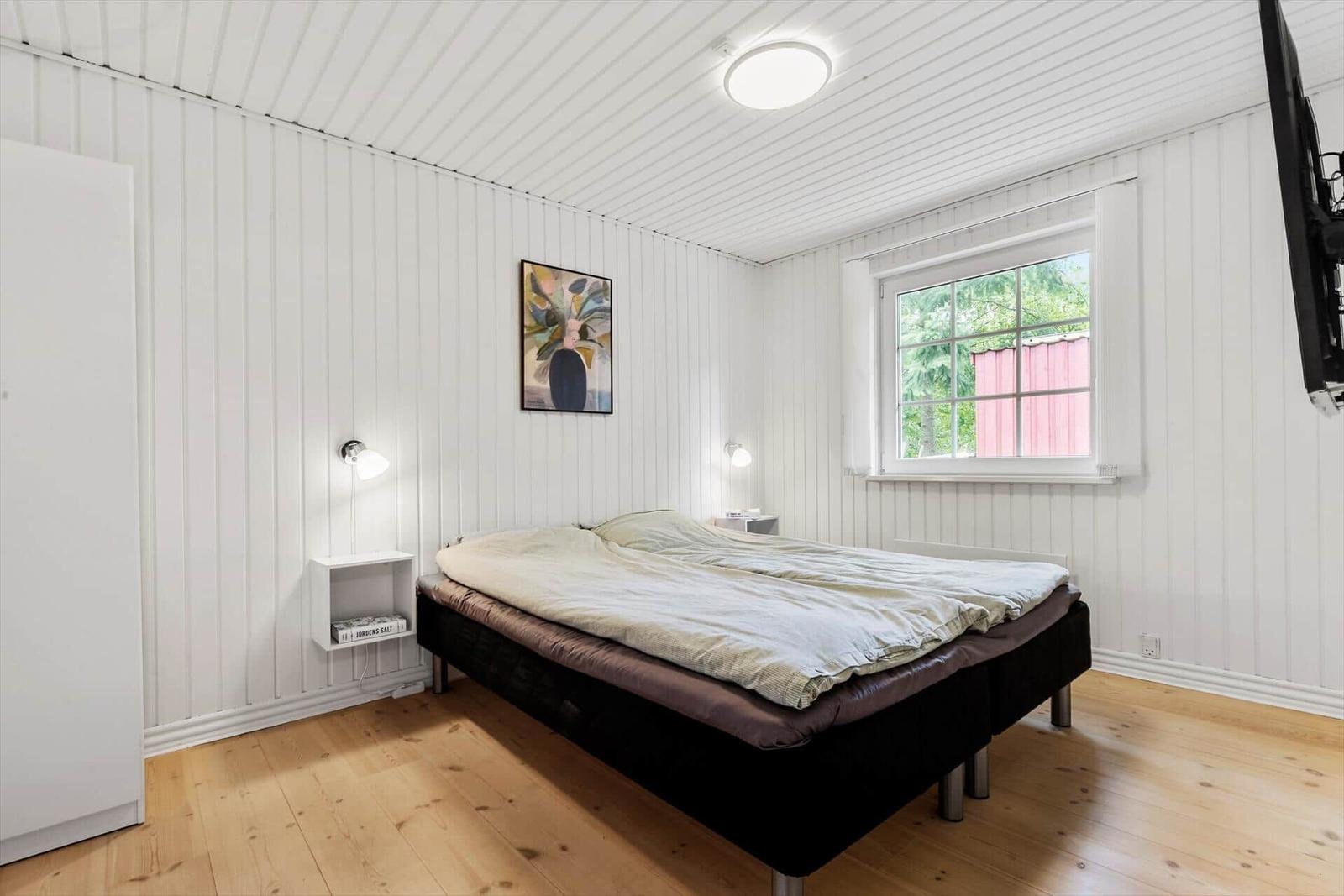 Schlafzimmer mit Bett, Fenster und Wandbild.