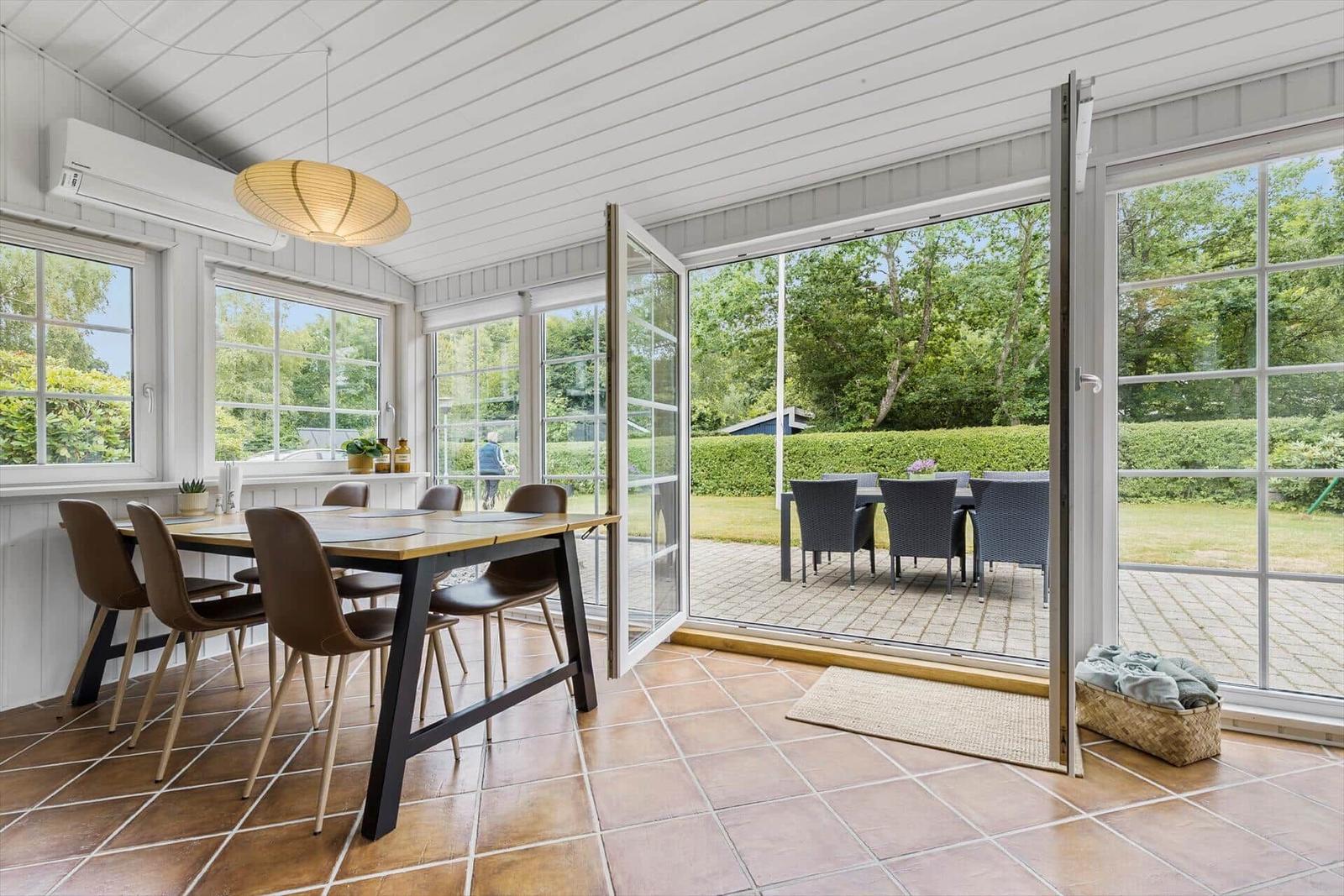 Essbereich mit Tisch und Stühlen, große Glastüren zu Terrasse mit Garten.