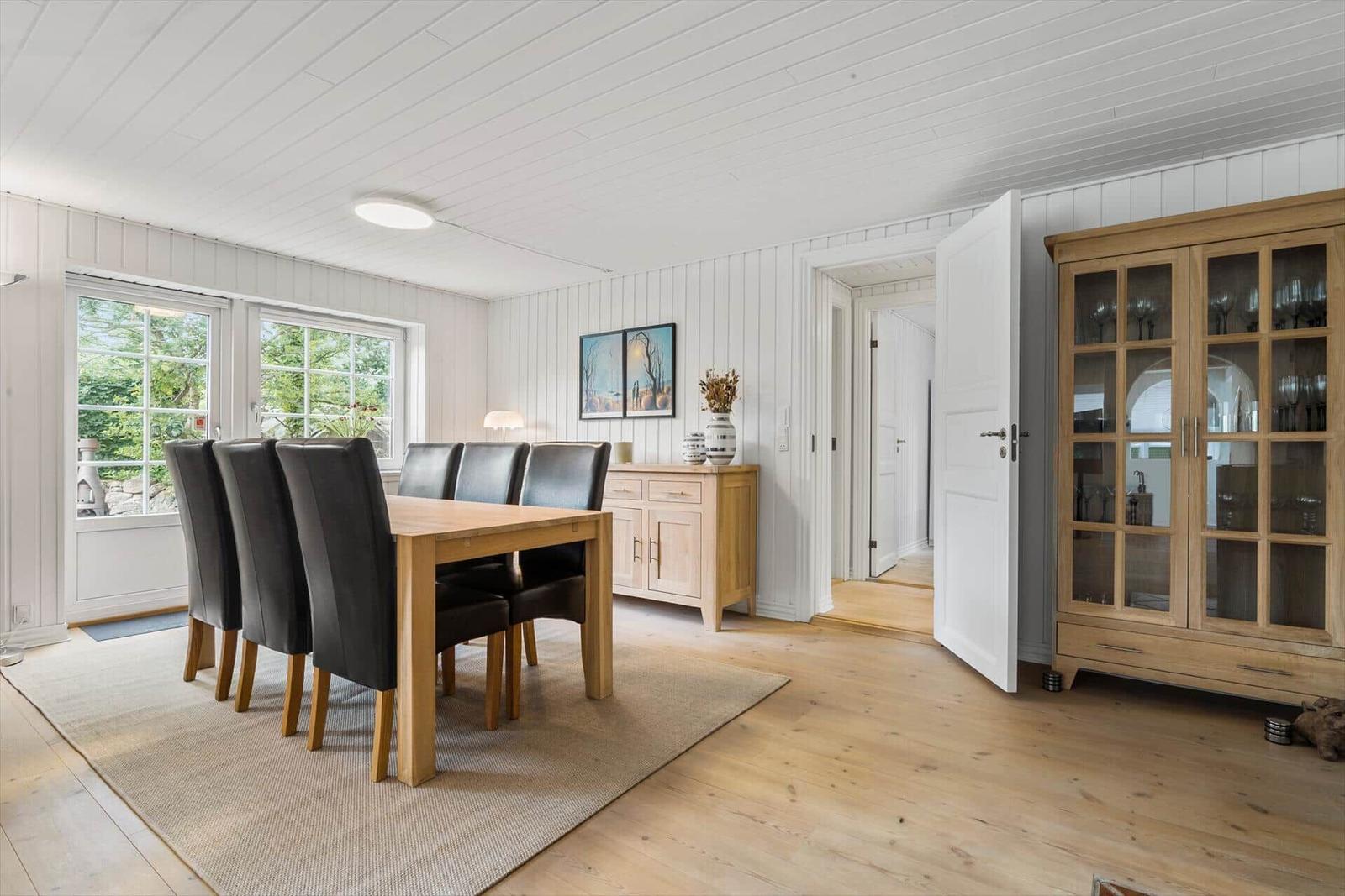 Esszimmer mit Holztisch, schwarzen Stühlen und Glasvitrine.