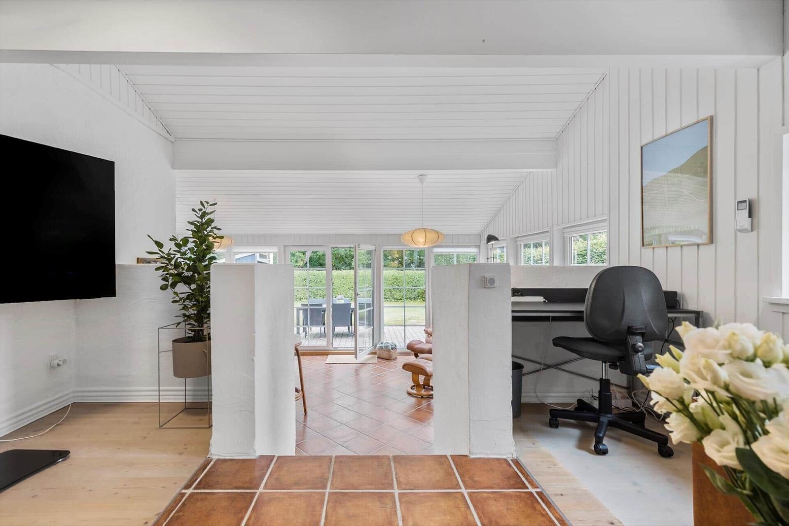 Wohnbereich mit TV, Arbeitsplatz und Blick auf die Terrasse.