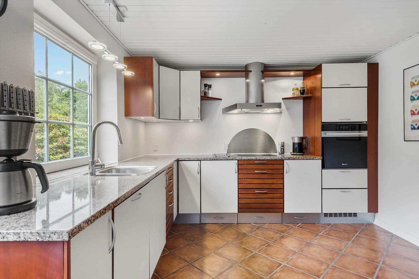 Küche mit Arbeitsfläche, Herd, Dunstabzug und Fenster.