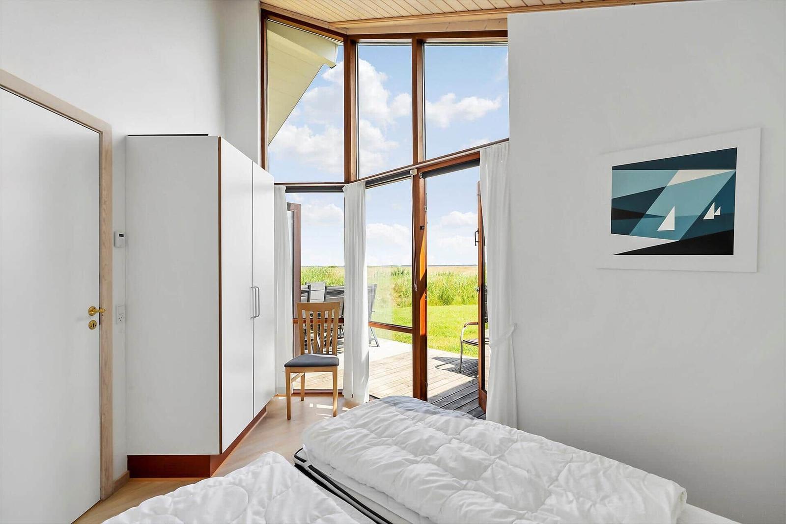 Schlafzimmer mit Blick auf Terrasse und Grünland.