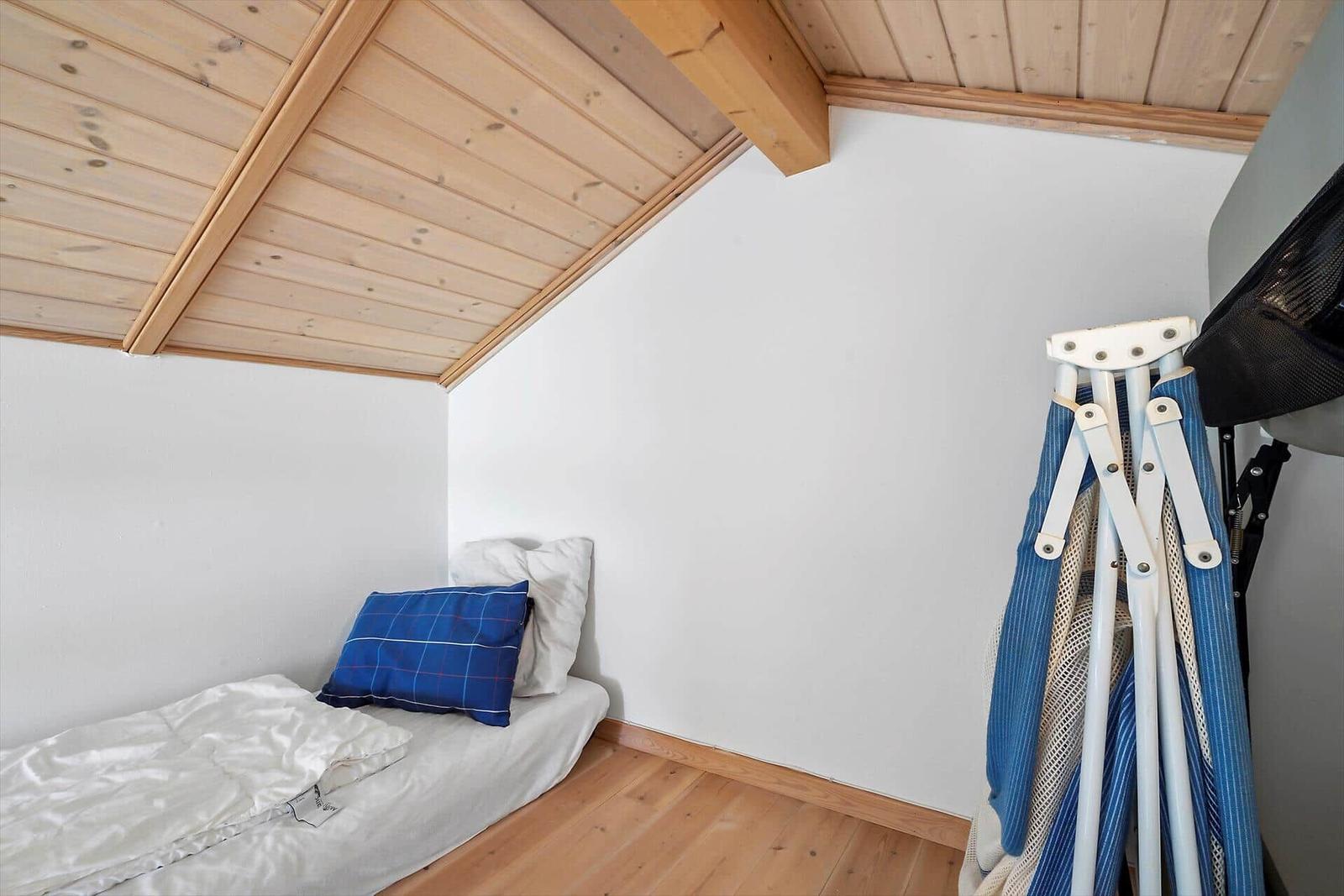 Ein Schlafzimmer mit Dachschrägen, Holzboden und einem Bett mit Kissen.