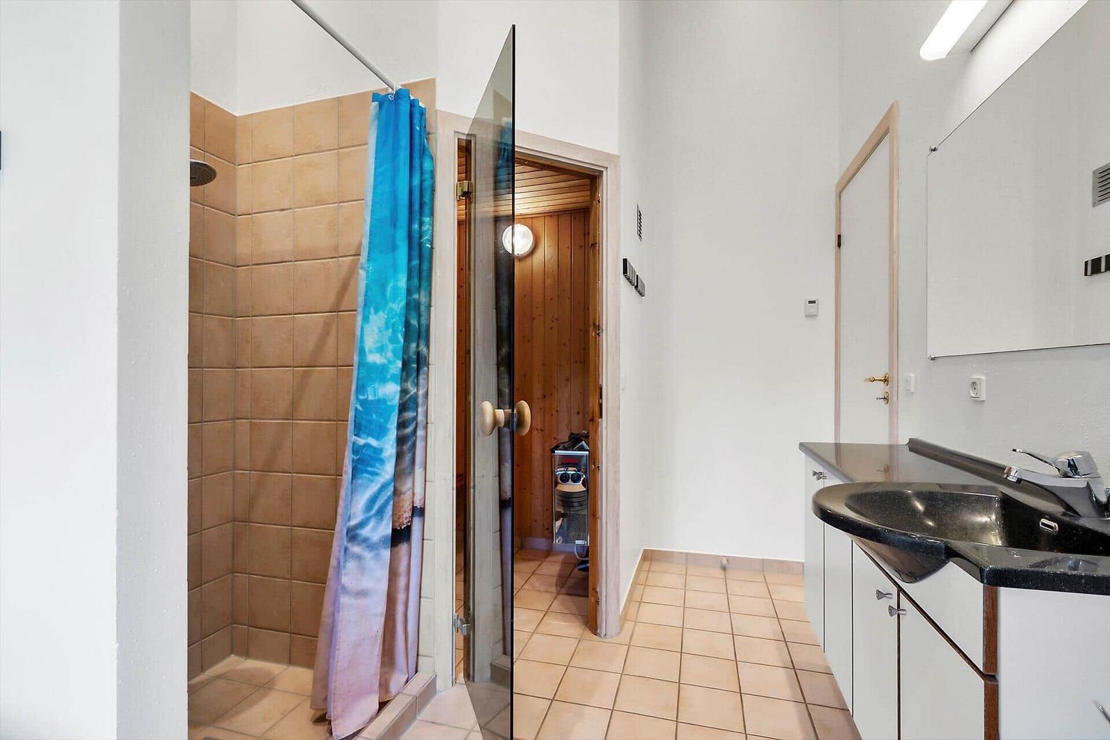 Badezimmer mit Dusche, Waschbecken und Sauna.