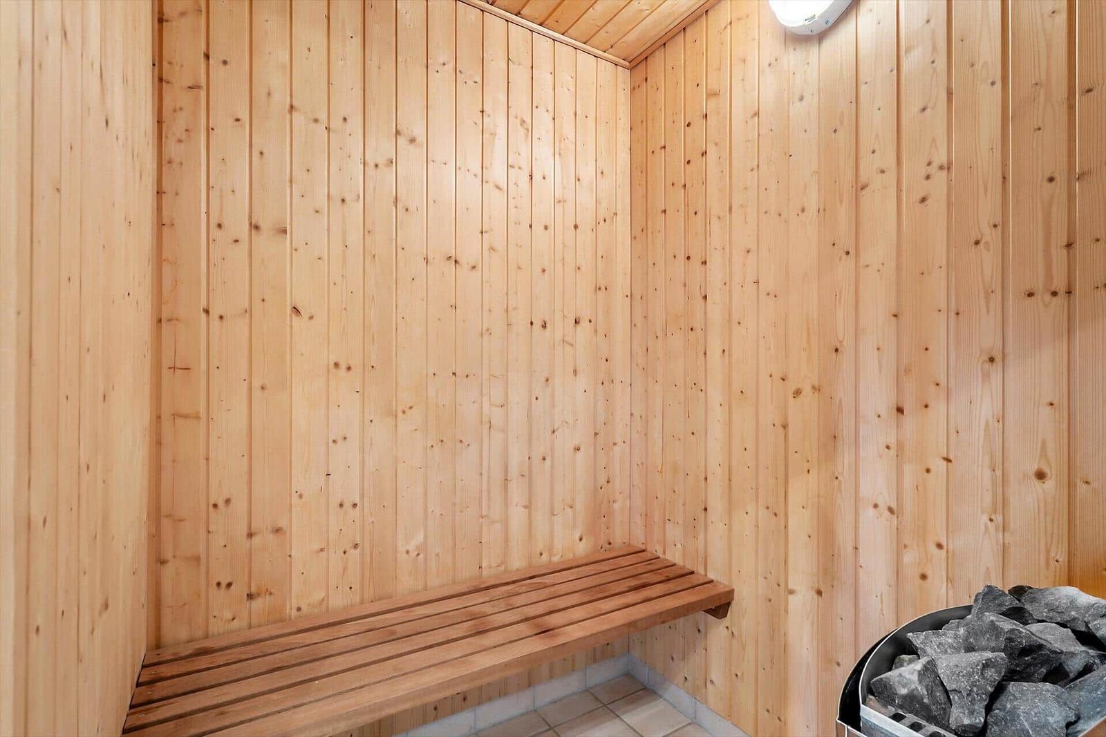 Sauna mit Holzwand und Sitzbank sowie Steinbehälter