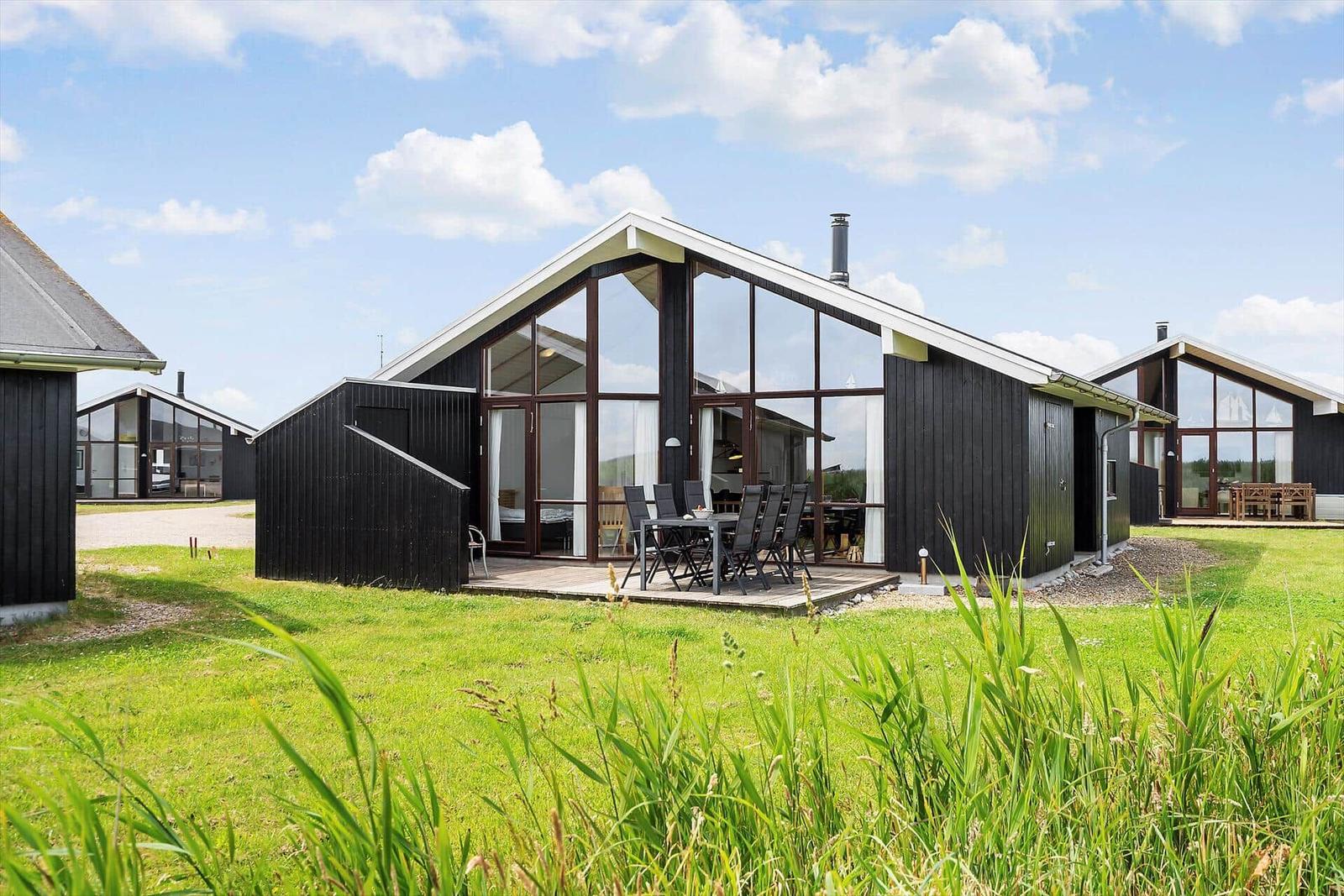 Moderne Holzhütte mit großem Glasbereich und Terrasse im Grünen.
