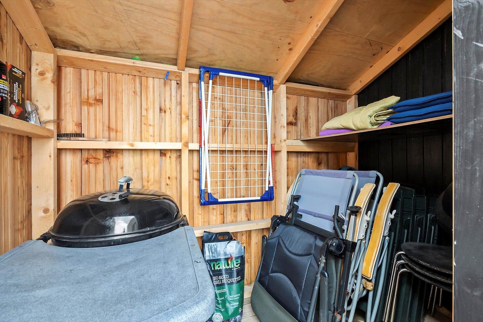 Schuppen mit Grill, Stühlen und Lagerregalen.