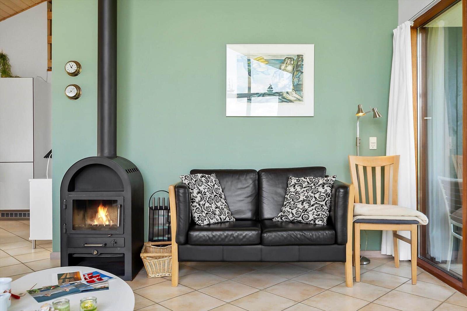 Ein Wohnzimmer mit Sofa, Kamin und Glastür. Wandfarbe ist grün.