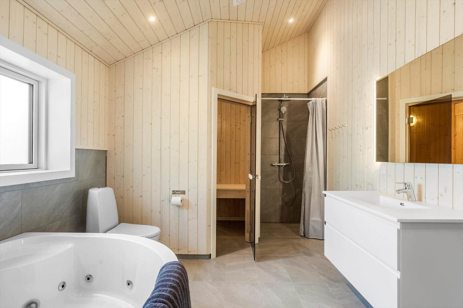 Bathroom with whirlpool, shower, and sauna. Wooden walls and white sink.