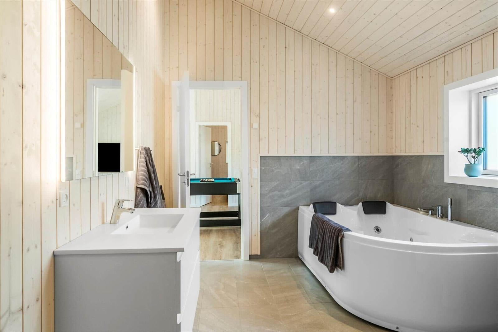 Bathroom with bathtub, sink, and wooden walls