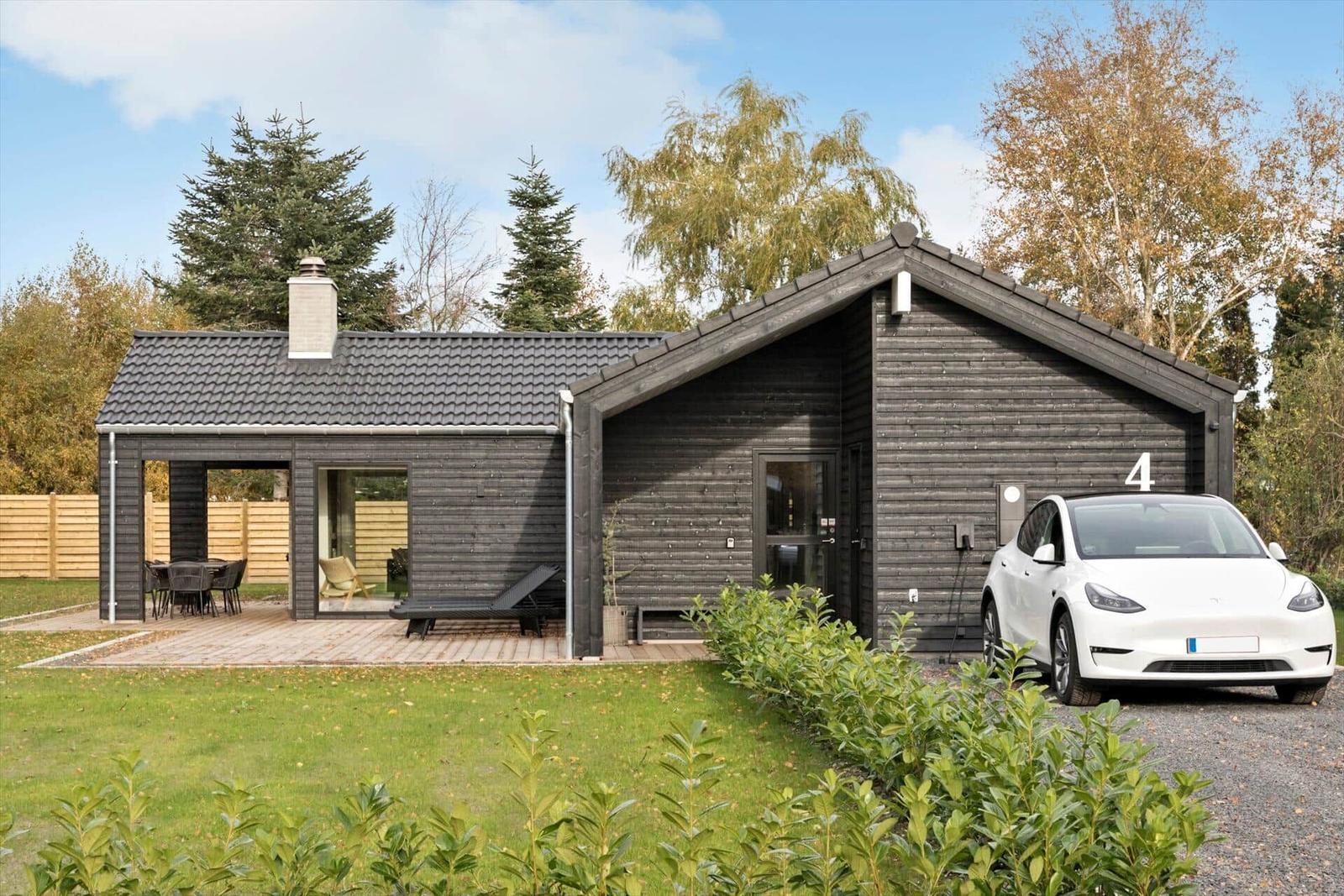 Modern wooden house with terrace, barbecue area, and parking for one car.
