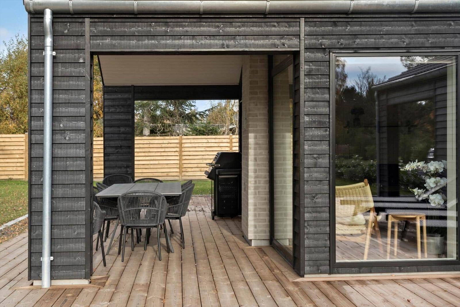 Deck with table, chairs, and grill. Wooden floor and large windows.