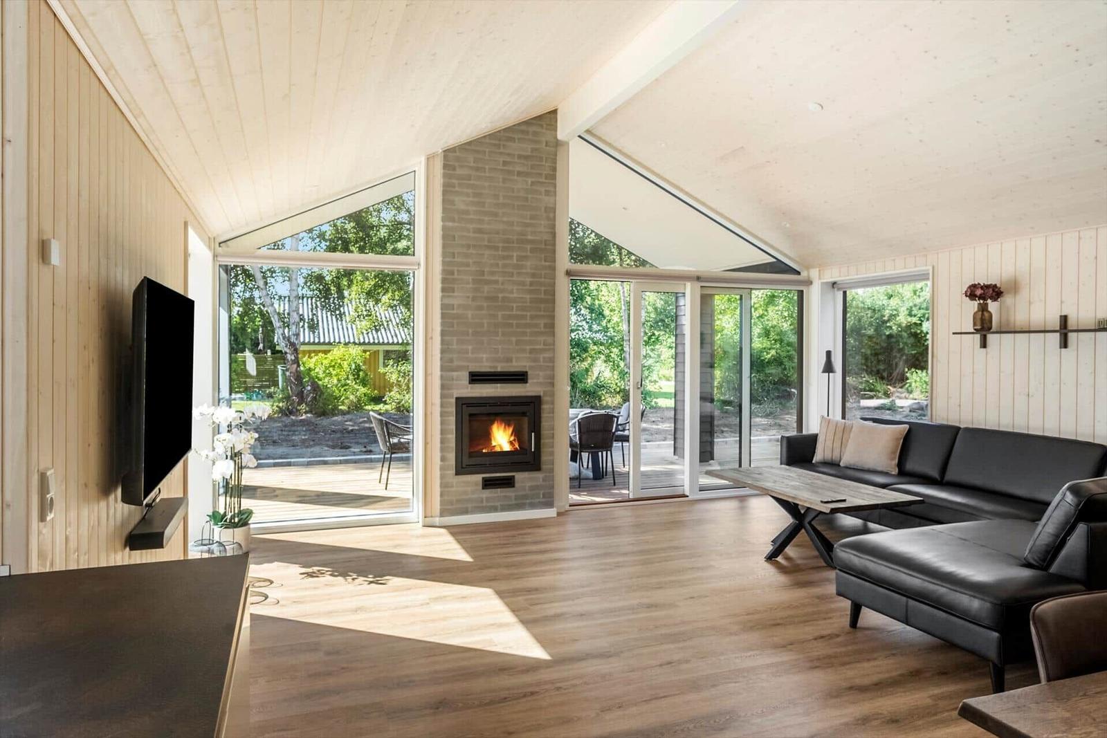 Living room with fireplace, TV, and large window view of garden