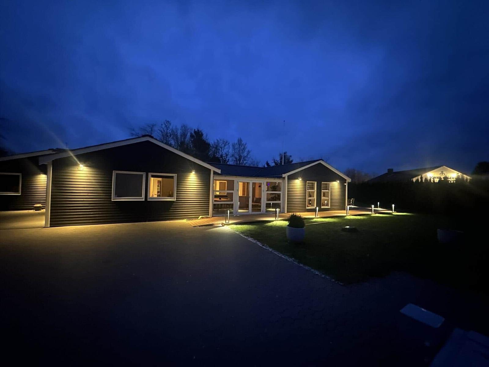 Modernes Haus mit beleuchteter Fassade und Terrasse bei Nacht.