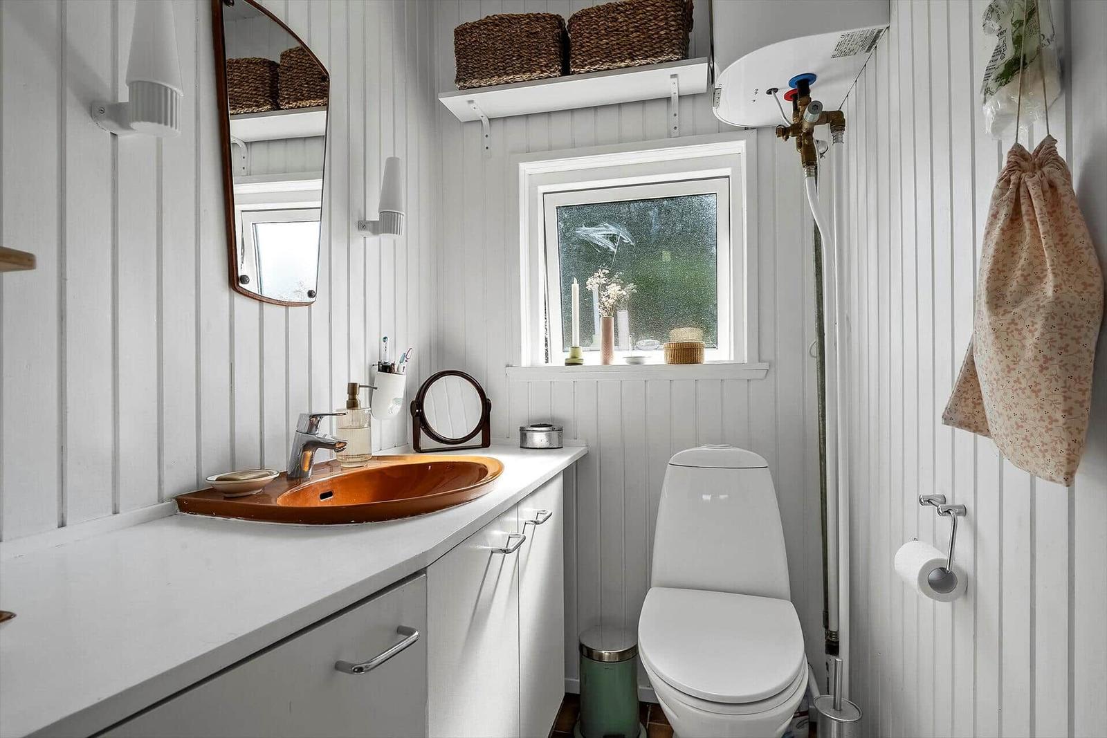 Badezimmer mit Waschbecken, Toilette und Fenster